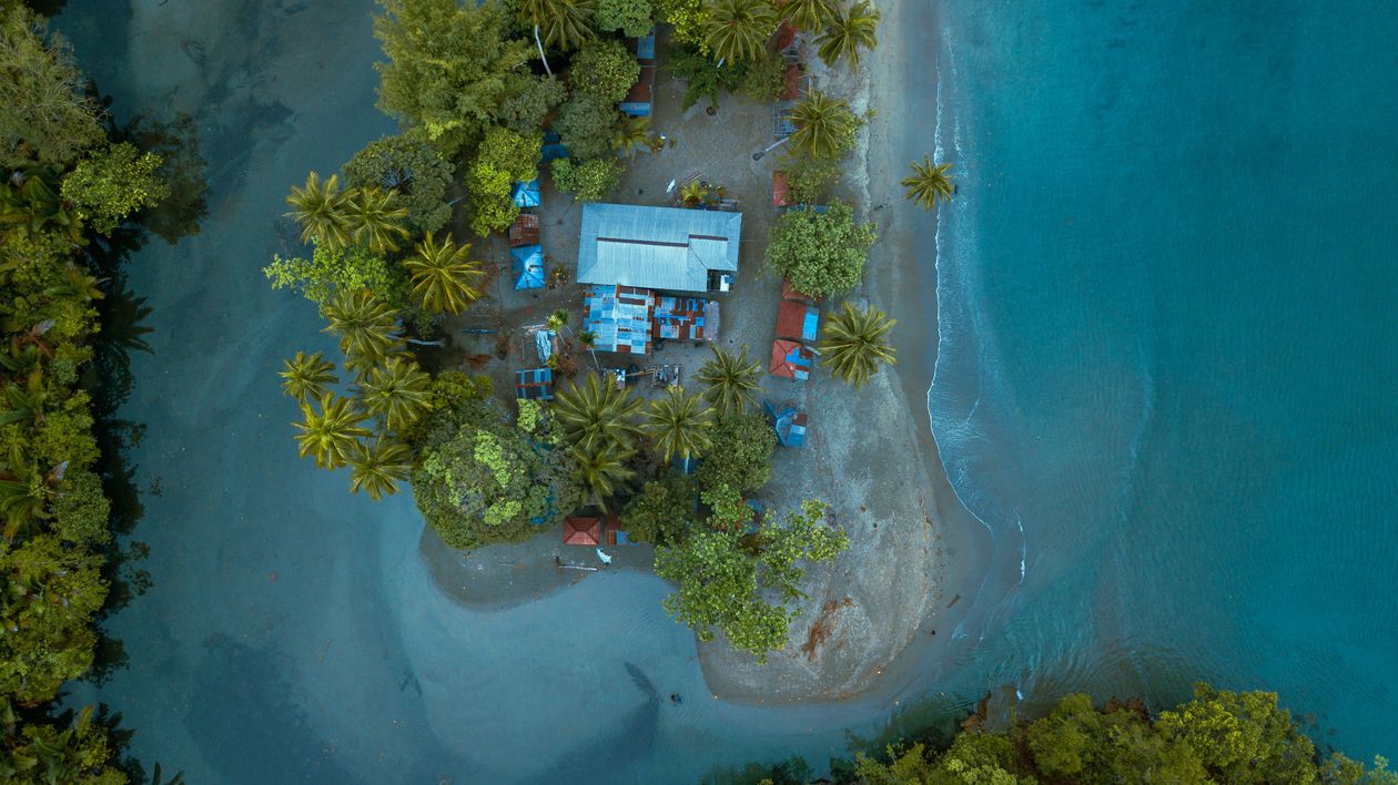 Aerial shot of tropical island buildings surrounded by turquoise sea