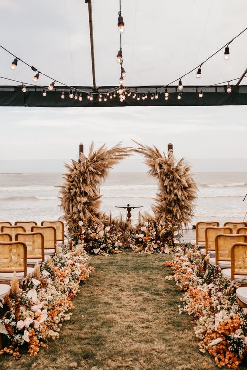 Beach wedding ceremony decorated with tropical flowers and white drapery