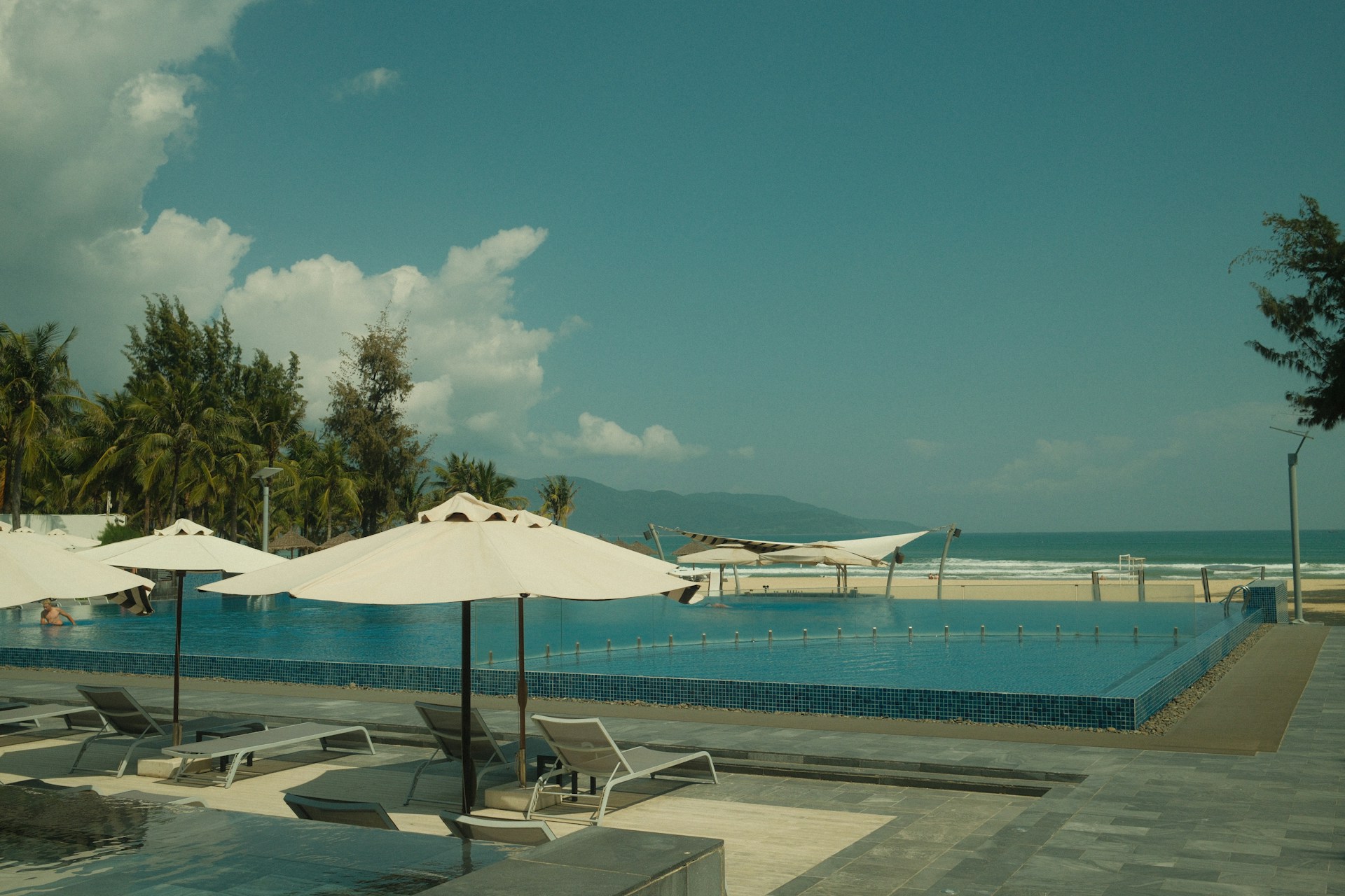 A wide pool deck and palm-fringed beach at a Sandals St Lucia property