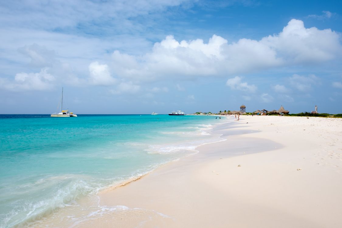 Sailing boat by a tropical beach with turquoise water and white sand