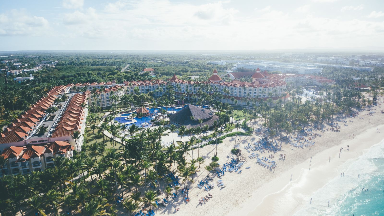 Aerial view of a Punta Cana beach resort with turquoise water, white sand, palm trees, and resort buildings