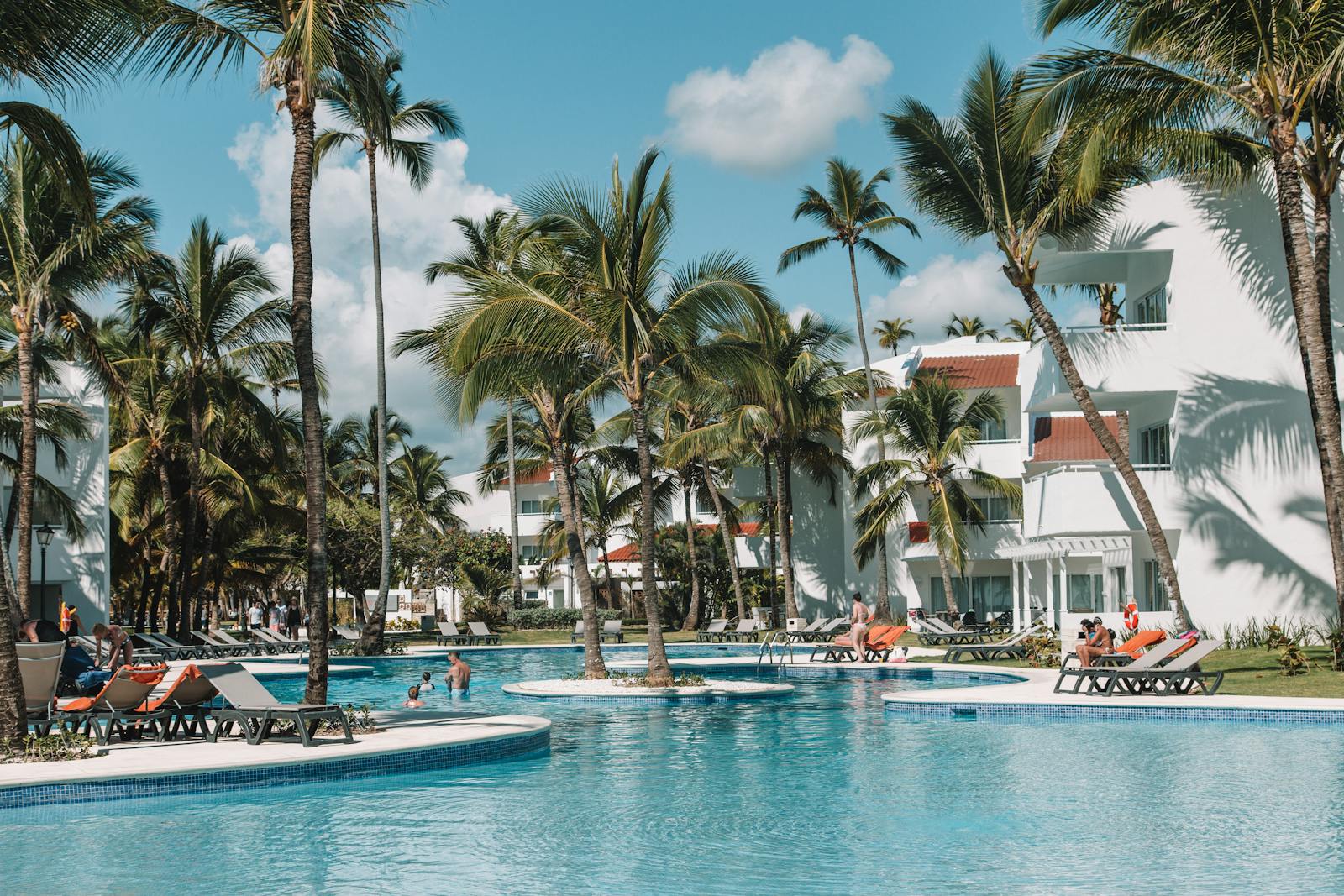 Family-friendly Caribbean resort pool with palm trees, turquoise water, and children enjoying the tropical setting