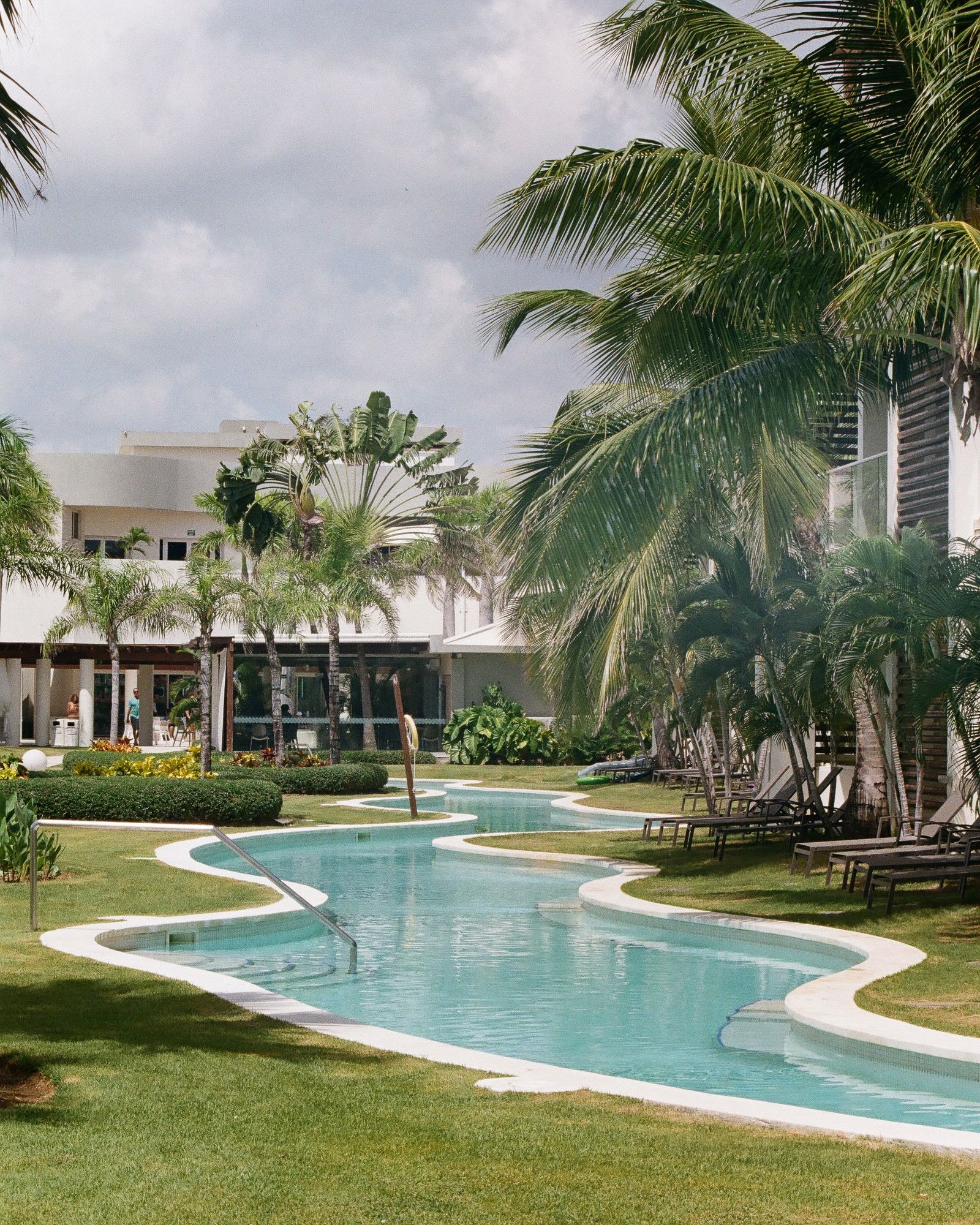 Tropical resort with winding swimming pool and lush palm tree landscaping