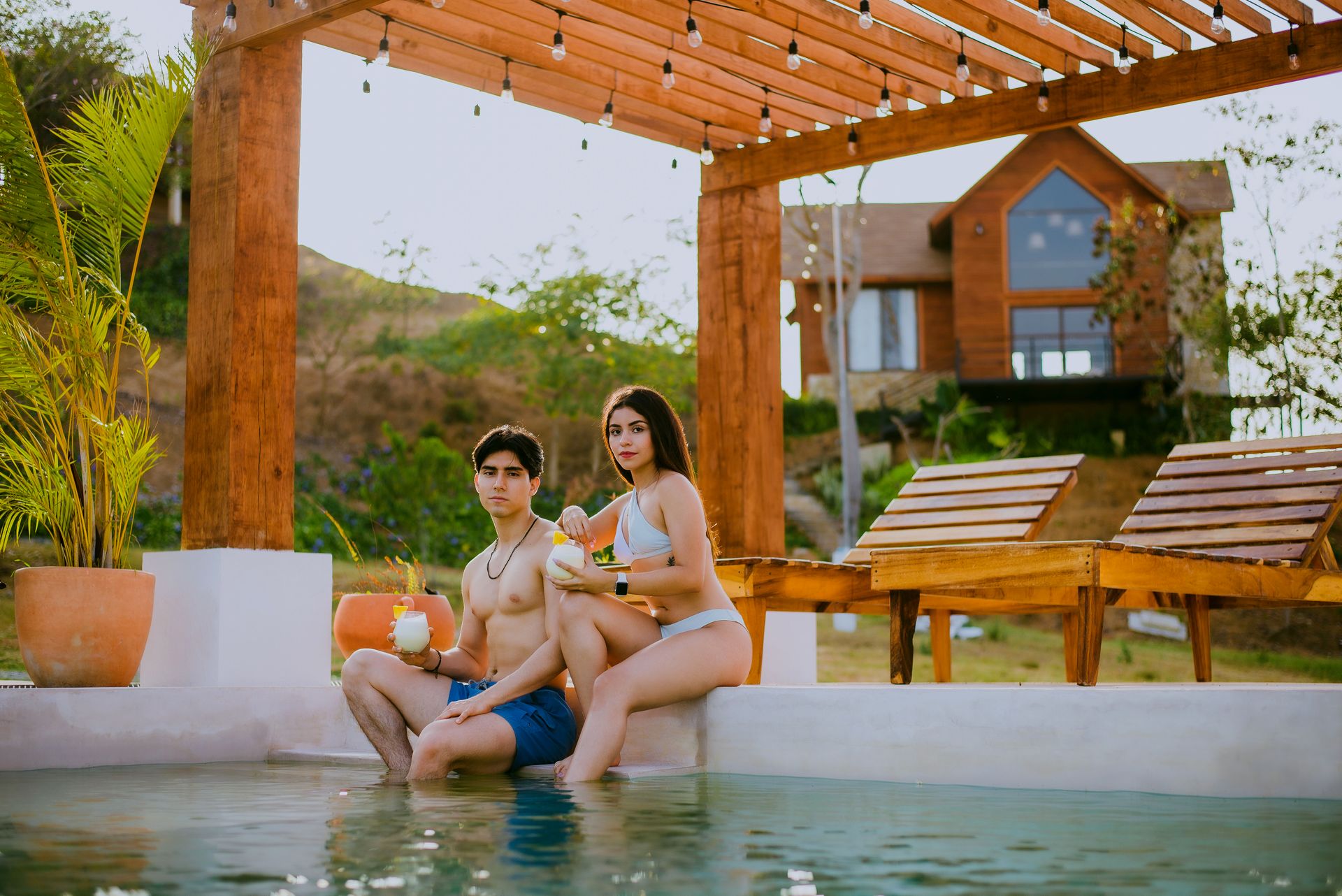 Couple enjoying drinks by the pool at a tropical resort
